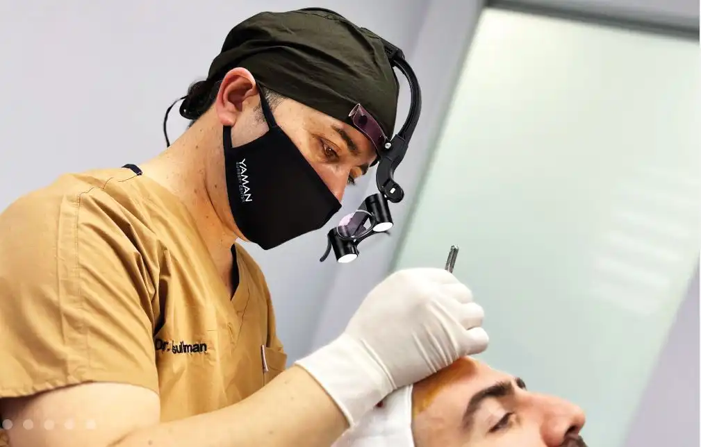 الدكتور رسول يمان اثناء اجراء عملية زراعة شعر لمريض