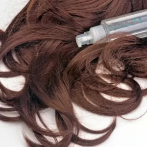 شعر سيدة عليه زجاجة دواء من أنواع المينوكسيديل
